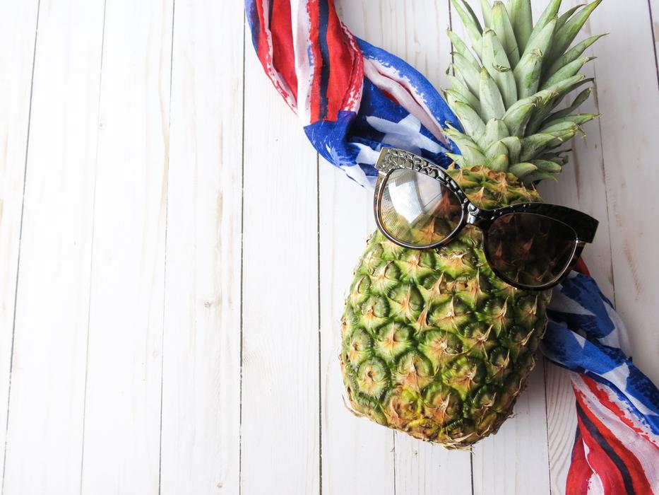 sunglasses on Pineapple above folded American Flag