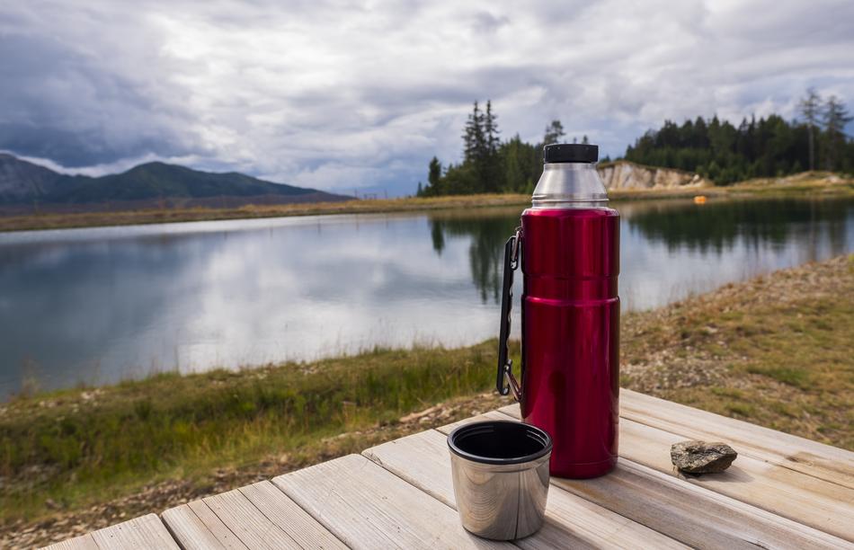 red thermos on a table by the lake