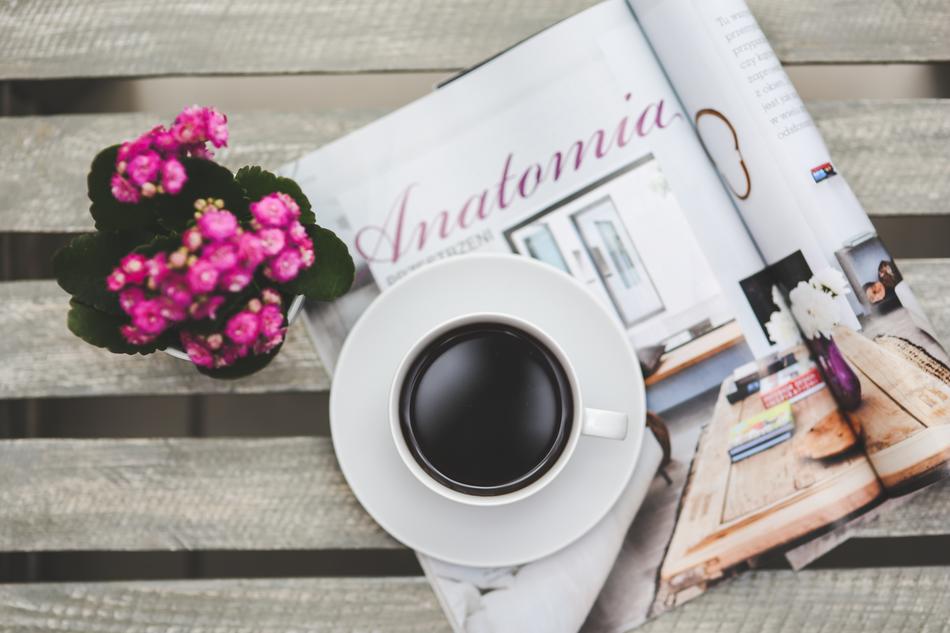 Beautiful, pink and purple flowers and beautiful cup of coffee, on the magazines, on the wooden surface