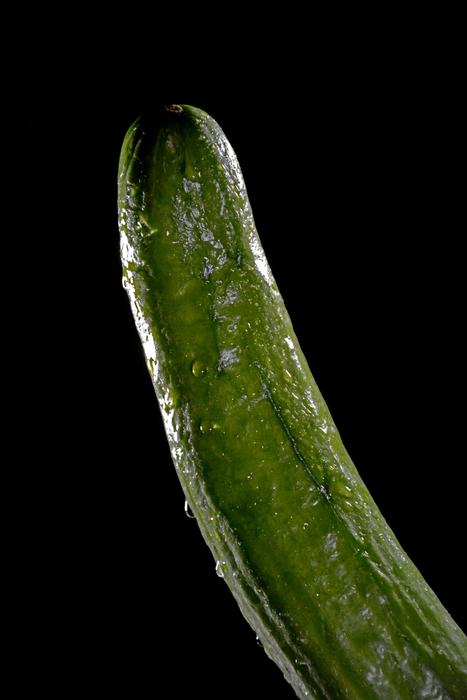 Ripe, green cucumber in light, at black background