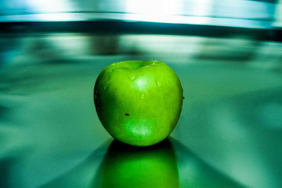 Close-up of the green apple in water drops at green and blue background