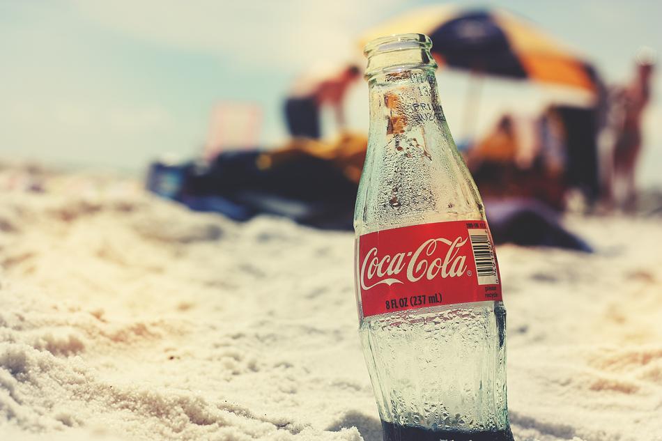 bottle of coca cola on the beach on a blurred background