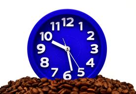 blue alarm clock on a pile of coffee beans