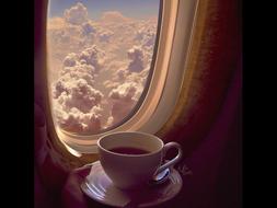 a cup of coffee near the window on an airplane