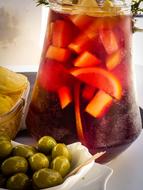 olives in a plate next to a jug of drink