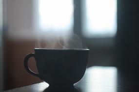 Beautiful cup of hot beverage with steam in light