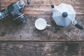 camera next to a cup of coffee on a wooden surface