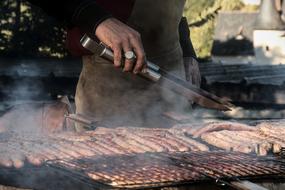 man fries sausages on the grill