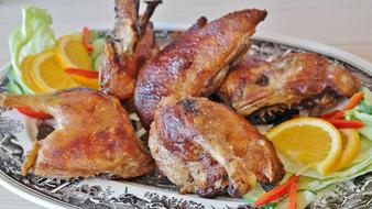 Beautiful roasted duck with the orange and colorful vegetables, on the black and white plate with images