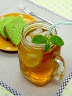 Beautiful and colorful ice lemon tea with fruits and straw, near the dessert on the plate