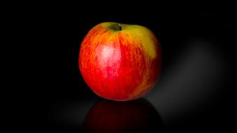 red ripe apple reflected on black background