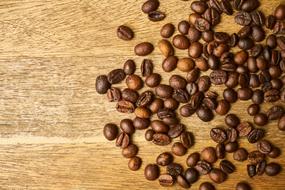 Close-up of the beautiful, brown coffee beans of different shades, on the wooden surface