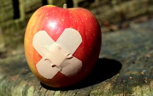 Beautiful and colorful, shiny apple with patch, on the wood, in sunlight