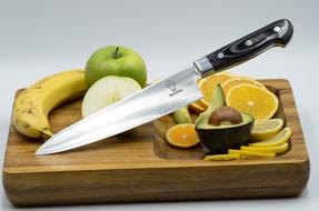 Knife and fruits on wood board