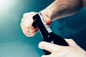 Man opening bottle of wine, in light