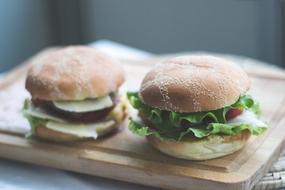 a couple of burgers on a wooden board