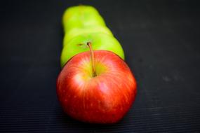 green and red apples on a dark surface