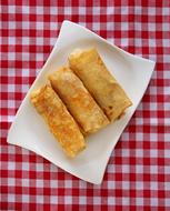 Beautiful, stuffed, fried slapjack desserts on the white plate, on the red and white, checkered cloth