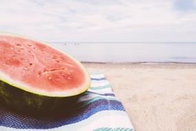 half a ripe watermelon on a striped towel