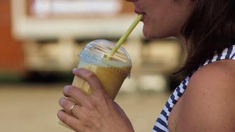 woman drinking yellow smoothie