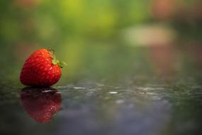 red strawberries on a reflective surface on a blurred background