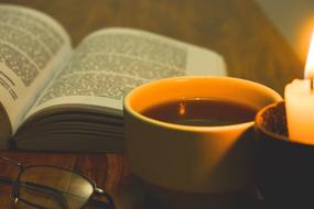 glasses and hot drink in cup in front of open Book, Reading