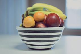 fruits in a ceramic bowl on a table on a blurred background