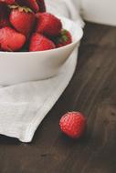 ripe Strawberries in white bowl on wooden table