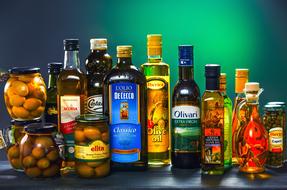bottles with olive olia next to jars of olives