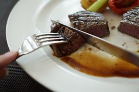 Cutting beautiful steak with the colorful vegetables, on the white plate