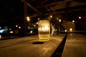 Shiny glass of beer, in light, at background with colorful lights, at the night