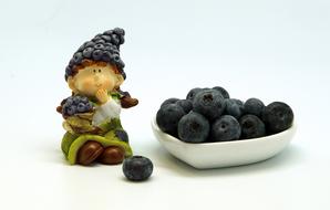 ceramic figurine near a plate with blueberries