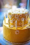yellow cake with a pattern of daisies and candles