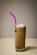 Coffee milkshake in the glass, with purple straw