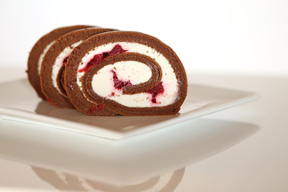 Beautiful baked brown, white roll dessert with pink and red cherries