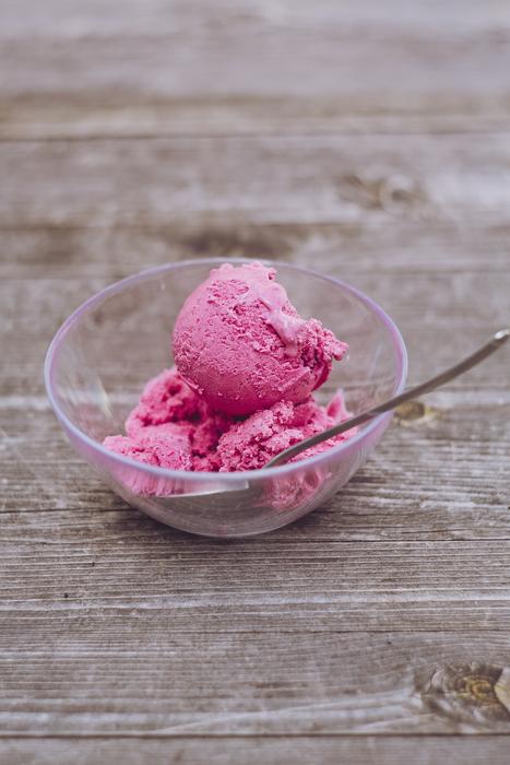 Beautiful, fresh, pink ice cream and spoon in the transparent bowl, on the wooden surface