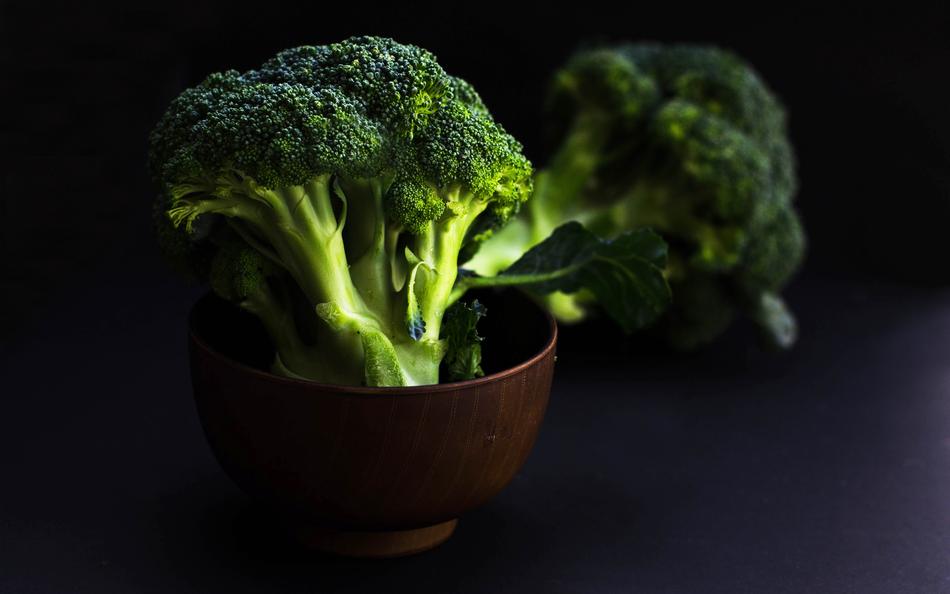 Beautiful, raw, green broccolis in bowls, in light, at dark background