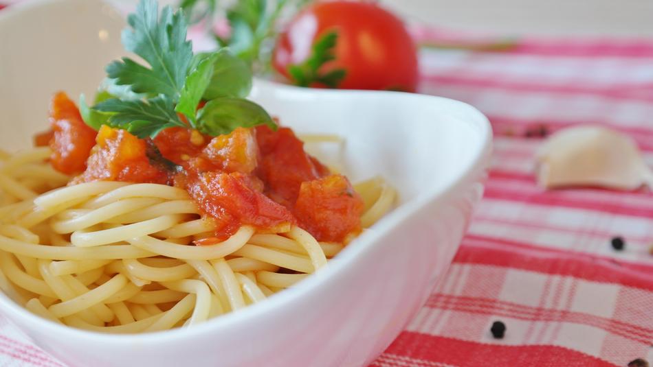 Beautiful and colorful spaghetti with tomatoes and greenery, on the checkered cloth