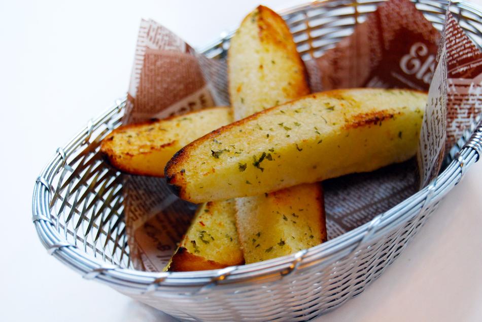 Close-up of the beautiful baked potatoes with herbs, in the metal basket with paper
