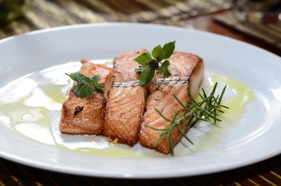Beautiful dish with salmon and herbs, on the white plate with yellow sauce