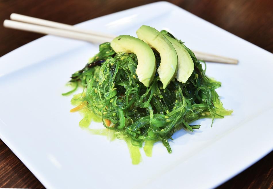 Beautiful, green salad with Wakame and avocado, on the white plate with chopsticks