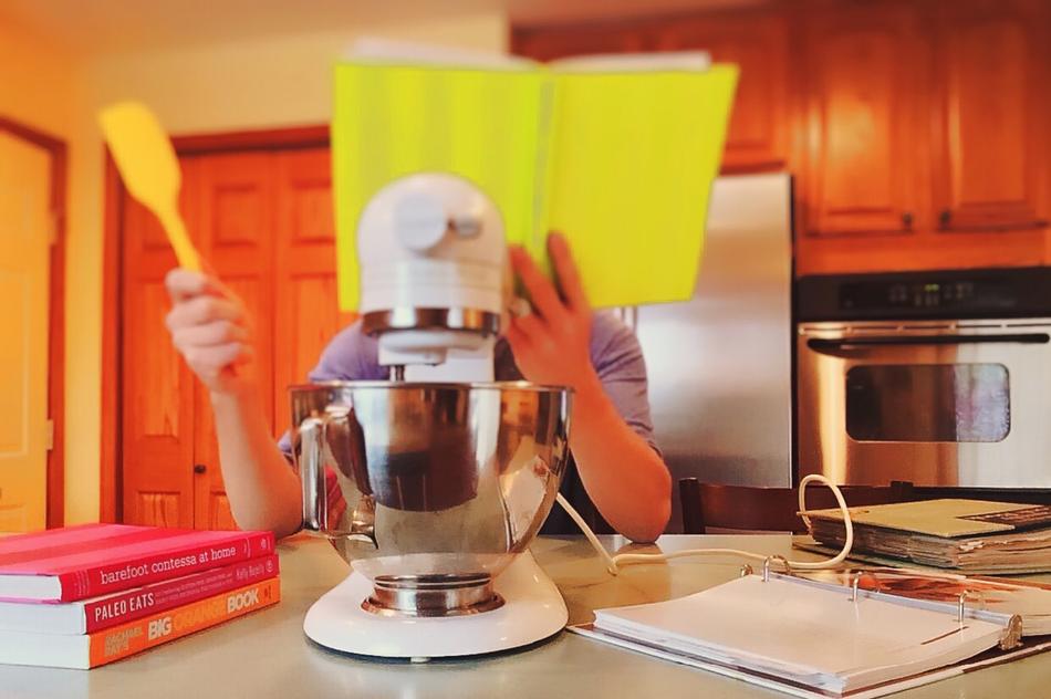 Cooking, person with book at face in Kitchen
