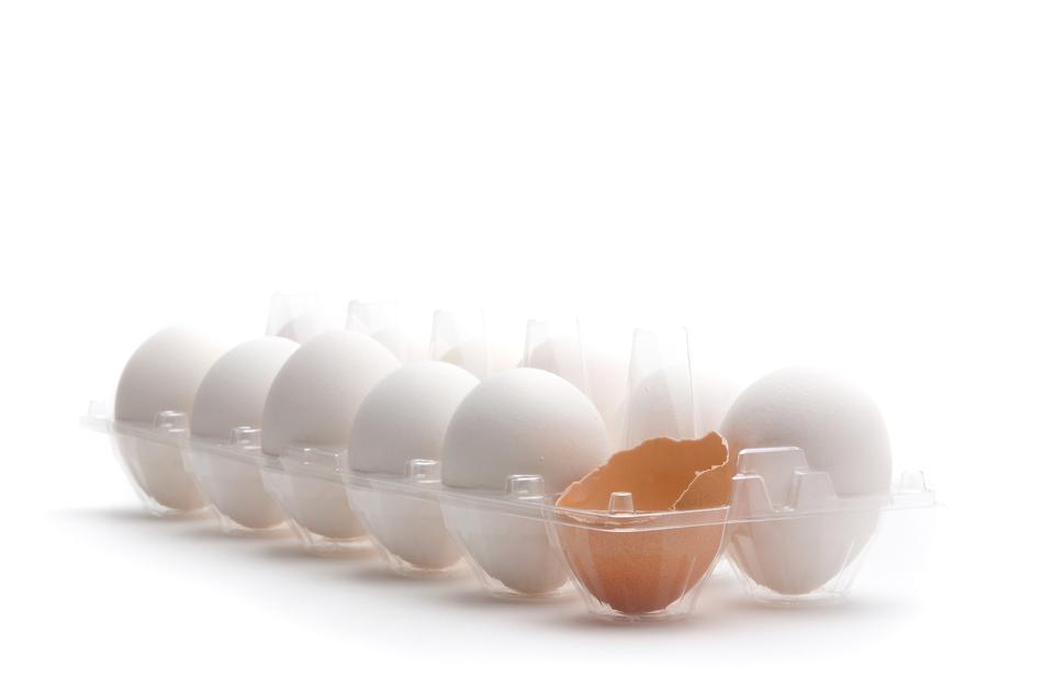 One cracked brown egg among the white in the package, at white background, clipart