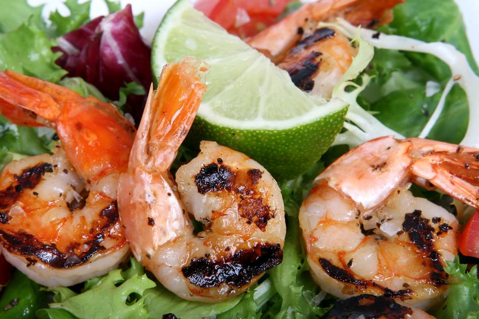 Close-up of the colorful Asian barbecue with shrimps, vegetables and lime