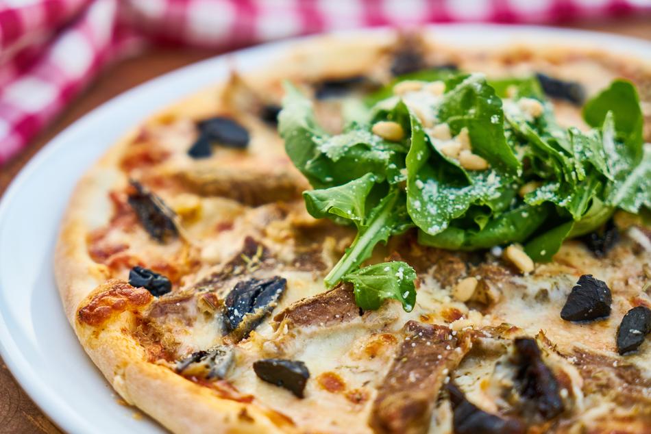 Beautiful pizza with green arugula, on the white plate