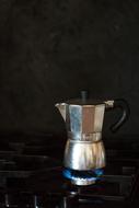 Close-up of the shiny, metal coffee pot on fire, in the kitchen