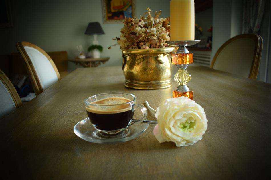 Close-up of the beautiful composition with the coffee in glass, near the white and green rose, candle and flower pot