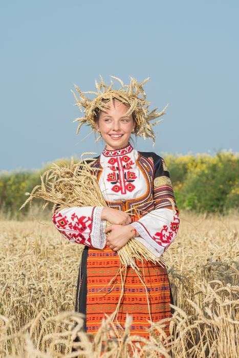 Harvest, happy young woman in folk costume with ripe wheat, bulgaria, burgas, sarafovo