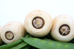 white carrots on pile of green pods