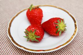 three strawberries in plate